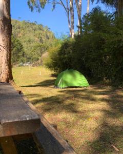 a green tent sitting in the grass next to a tree at Hotel Fazenda Boa Esperança in Delfim Moreira