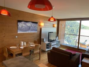 a living room with a table and a television at Paradiski pied des pistes plan peisey in Peisey-Nancroix