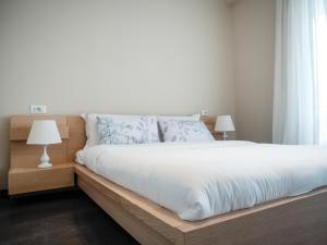 um quarto com uma cama com uma estrutura de madeira e 2 candeeiros em Lake Drive Rooms&Apartments em Tirana
