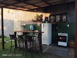 an outdoor kitchen with a table and chairs and a refrigerator at Temporada Casa dos Paiva in Barreirinhas
