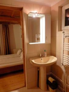 a bathroom with a sink and a mirror and a bed at Casa din Zori in Muntele Băişorii
