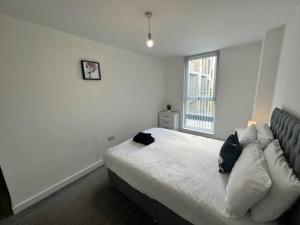 a white bedroom with a bed and a window at XL 2 Bed Central MCR Apt Sleeps 7 in Manchester