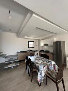 eine Küche mit einem Tisch mit Stühlen und einem Kühlschrank in der Unterkunft Duplex Taghazout Bay in Taghazout