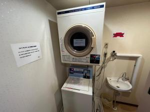 ein Badezimmer mit einer Waschmaschine und einem Waschbecken in der Unterkunft Hotel Axia Inn Kushiro in Kushiro