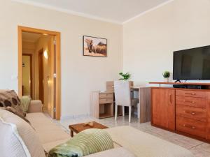 a living room with a couch and a flat screen tv at CASA TÔMBUA - Pool - Beach & Center 300m - AC - WiFi in Carvoeiro