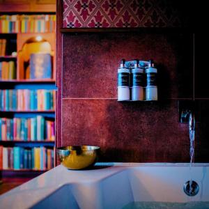 uma estante de livros com duas garrafas em cima de um lavatório em The George Hotel em Inveraray