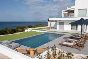 a house with a swimming pool next to the ocean at Nouvelle Villa in Ierápetra