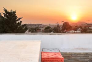 a bench sitting on a wall with the sunset in the background at Secret Garden Home Lagonissi Attiki in Foinikiá