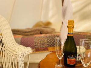 Una botella de champán y dos copas en una mesa. en tent romantica a b&b in a luxury glamping style, en Mariefred