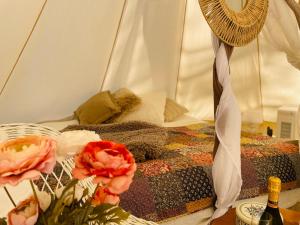 Una cama en una tienda de campaña con flores y una botella de vino en tent romantica a b&b in a luxury glamping style en Mariefred