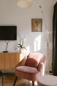 a living room with a chair and a tv and a lamp at BnB Manere in Grimbergen