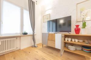 a living room with a tv and a shelf with dishes at Golden Home in Treviso