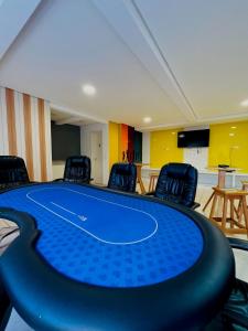 a ping pong table in a room with chairs at Condominio Club, Vista para o mar, Churrasqueira in Guarujá