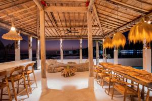 einen Pavillon mit Tischen, Stühlen und einem Sofa in der Unterkunft Sunset House Ceningan, 10 person beachfront private villa in Nusa Lembongan