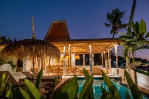 a villa with a swimming pool at night at Sunset House Ceningan, 10 person beachfront private villa in Nusa Lembongan