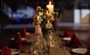 einen Tisch mit einer Kerze und eine Vase mit Blumen in der Unterkunft De Foret in Havelock Island