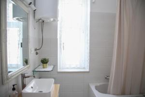 La salle de bains est pourvue d'un lavabo, d'une baignoire et d'une fenêtre. dans l'établissement Lux Apartment Duje, à Split