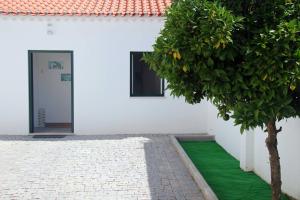 a white building with a tree next to a door at Inncork Guesthouse in Ponte de Sor