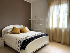 Cette chambre comprend un lit blanc avec des oreillers jaunes et une fenêtre. dans l'établissement Casa Isore con 3 camere da letto, à Pesaro