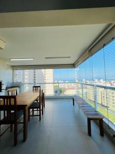 een eetkamer met een tafel en stoelen op een balkon bij Condominio Club, Vista para o mar, Churrasqueira in Guarujá