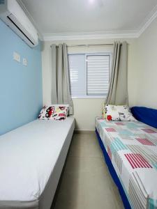 a bedroom with two beds and a window at Condominio Club, Vista para o mar, Churrasqueira in Guarujá