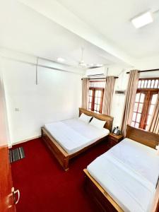 two beds in a room with two windows at KINGS HOTEL in Colombo