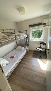 a bedroom with bunk beds with a chair and a window at TERRASSES DE MALMEDY- CHALET 108 Le Chalet du Cerf & TRIPLEX 223 Le Refuge du Cerf in Malmedy