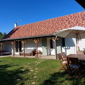 a house with a table and chairs and an umbrella at Florie Cottage in Cserszegtomaj