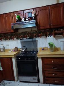 cocina con fogones y algunos armarios de madera. en Espacio familiar Poma en Machala