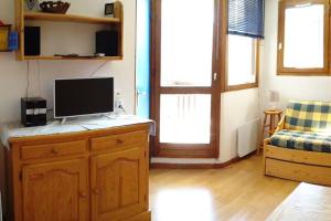 a living room with a television on a wooden cabinet at Paradiski proches pistes et commerces vallandry in Landry