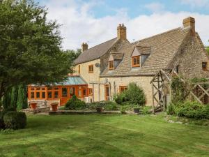 an exterior view of a large stone house with a yard at Manor Farm in Cheltenham