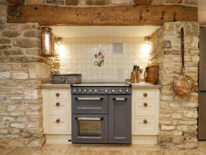 a kitchen with a stove and a stone wall at Manor Farm in Cheltenham