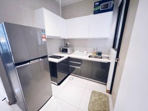 eine kleine Küche mit weißen Schränken und einem Kühlschrank in der Unterkunft [PROMO]Connected train 2 Bedroom (ABOVE MALL)8 in Kuala Lumpur