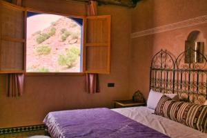 een slaapkamer met een bed en een groot raam bij DAR NOUR in Tafraoute