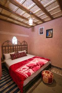 um quarto com uma cama grande e um cobertor vermelho em DAR NOUR em Tafraoute