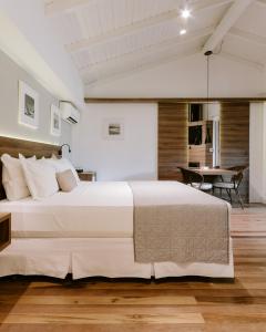 Un dormitorio con una gran cama blanca y una mesa en Hospedaria das Brisas, en Praia do Rosa