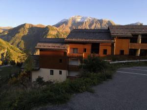 um edifício numa colina com montanhas ao fundo em Très Joli T2 aux pieds des pistes avec Balcon em Orcières