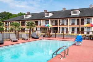 a pool in front of a inn with chairs and umbrellas at Baymont by Wyndham Commerce GA Near Tanger Outlets Mall in Commerce