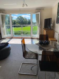 a living room with a glass table and chairs and a large window at River Penthouse Little Paxton - 75 Skipper Way in Saint Neots