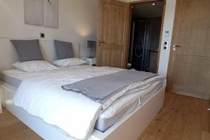 uma grande cama branca num quarto com pisos em madeira em Paradiski nouveau, calme et ensoleillé vallandry em Landry