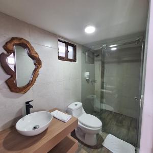 uma casa de banho com um lavatório, um WC e um espelho. em Balcones del Ayer em Salento