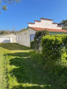 a house with a grassy yard next to a building at Mimizan Surf & Beach House 250m océan + forêt in Mimizan