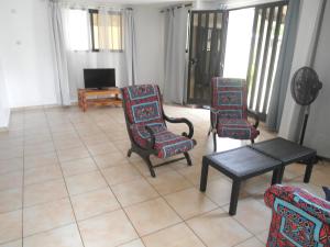 a living room with chairs and a table and a tv at Appartement d'une chambre a Grand Popo a 10 m de la plage avec piscine partagee jardin clos et wifi in Grand-Popo