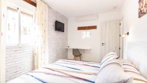 ein Schlafzimmer mit einem Bett und einem Fernseher an der Wand in der Unterkunft Cortijo La Venta Hoyo in Nigüelas