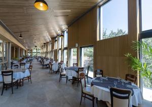 une salle à manger avec des tables, des chaises et des fenêtres dans l'établissement Domaine Lou Capitelle & Spa, à Vogüé