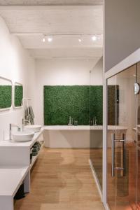 La salle de bains est pourvue de 2 lavabos et d'un mur vert. dans l'établissement BnB Manere, à Grimbergen