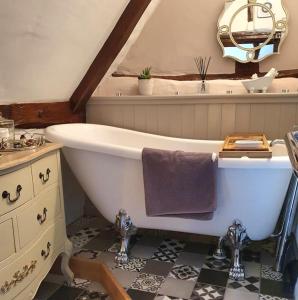 a bathroom with a white bath tub and a sink at Shoemakers Cottage, Halesworth in Halesworth