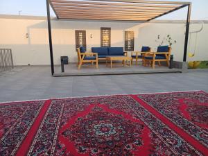 a patio with chairs and a red rug on a floor at شاليه الإفرند الفندقي فيلا in Buraydah