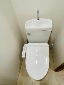 a white toilet in a bathroom with a remote control at STUDIO YONEGAHAMA l 米が浜通 in Yokosuka