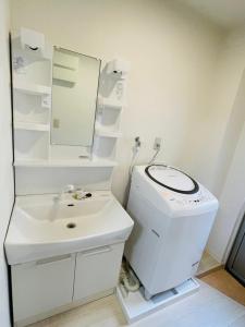 a white bathroom with a toilet and a sink at STUDIO YONEGAHAMA l 米が浜通 in Yokosuka